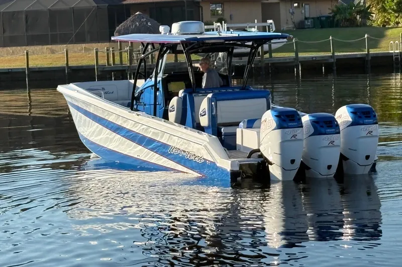 Slide: The Image of 2023 Nor-Tech 390 Sport Center Console boat with triple engines on calm water. - 2