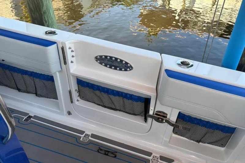 Slide: The Image of 2023 Nor-Tech 390 Sport Center Console boat interior with blue accents and storage compartments. - 23
