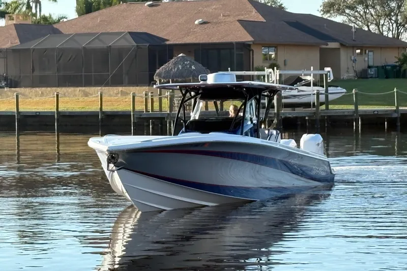 Slide: The Image of 2023 Nor-Tech 390 Sport Center Console boat cruising on calm water near residential docks. - 3