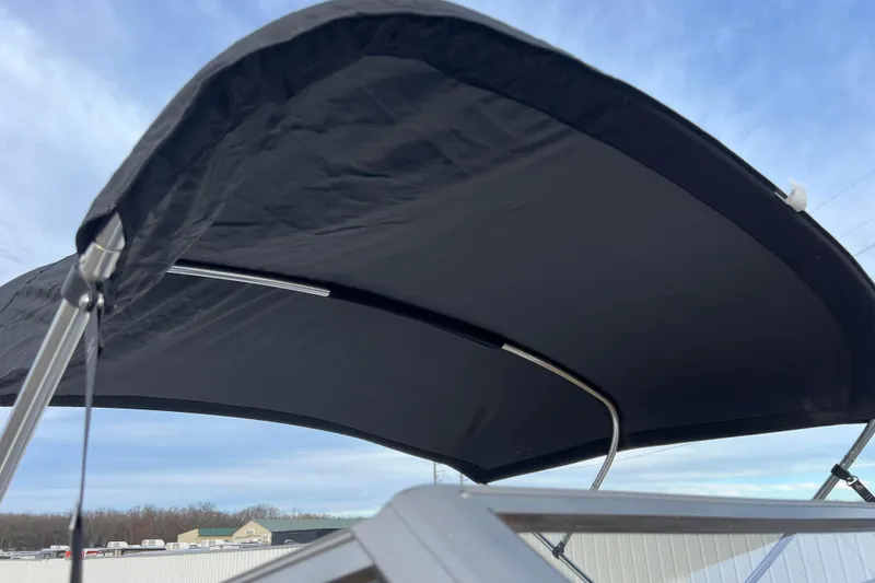 Slide: The Image of 2013 Larson LX 205S IO boat with black bimini top against blue sky. - 12