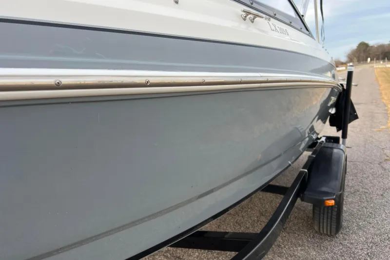 Slide: The Image of 2013 Larson LX 205S IO boat on trailer, side view, gray and white exterior. - 50