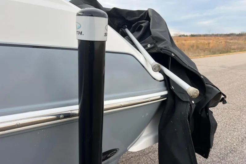 Slide: The Image of 2013 Larson LX 205S IO boat with cover and support poles on a road. - 54