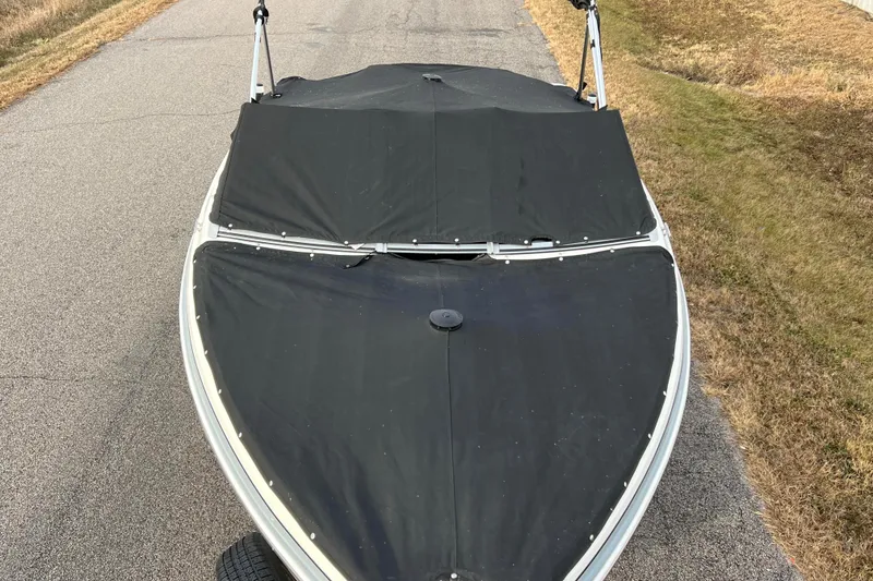 Slide: The Image of 2013 Larson LX 205S IO boat with black cover on a road. - 60