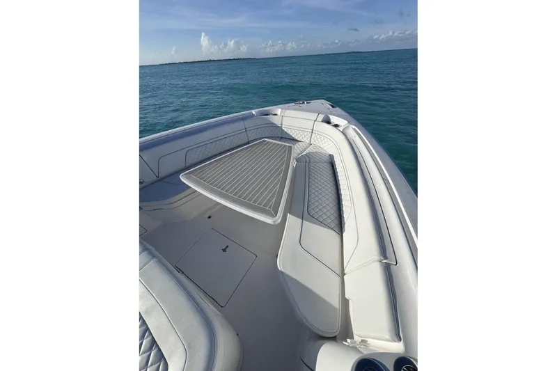 Slide: The Image of 2023 Intrepid 427 Nomad SE boat cruising on open blue ocean near city skyline. - 16