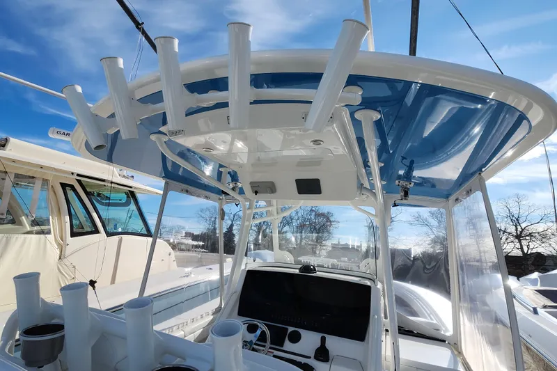 Slide: The Image of 2019 Regulator 34SS boat interior with rod holders and blue canopy under clear sky. - 10