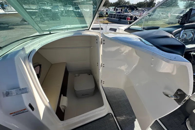Slide: The Image of 2015 Chaparral 246 boat interior with open cabin door and compact toilet. - 39