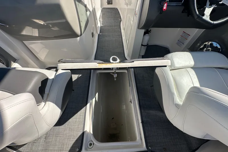 Slide: The Image of 2015 Chaparral 246 boat interior with open storage compartment and white seating. - 41