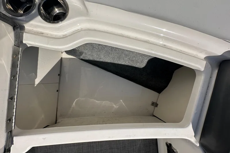 Slide: The Image of Storage compartment in a 2015 Chaparral 246 boat, featuring cup holders and carpeted interior. - 52