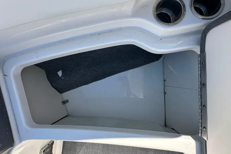 Slide: The Image of Storage compartment in a 2015 Chaparral 246 boat, featuring cup holders and carpeted interior. - 54