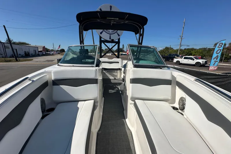 Slide: The Image of 2015 Chaparral 246 boat interior with seating, windshield, and canopy at a sales lot. - 61