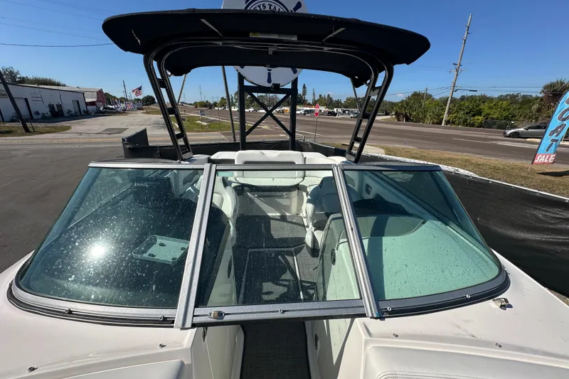 Slide: The Image of 2015 Chaparral 246 boat with open windshield, parked outdoors on a sunny day. - 66