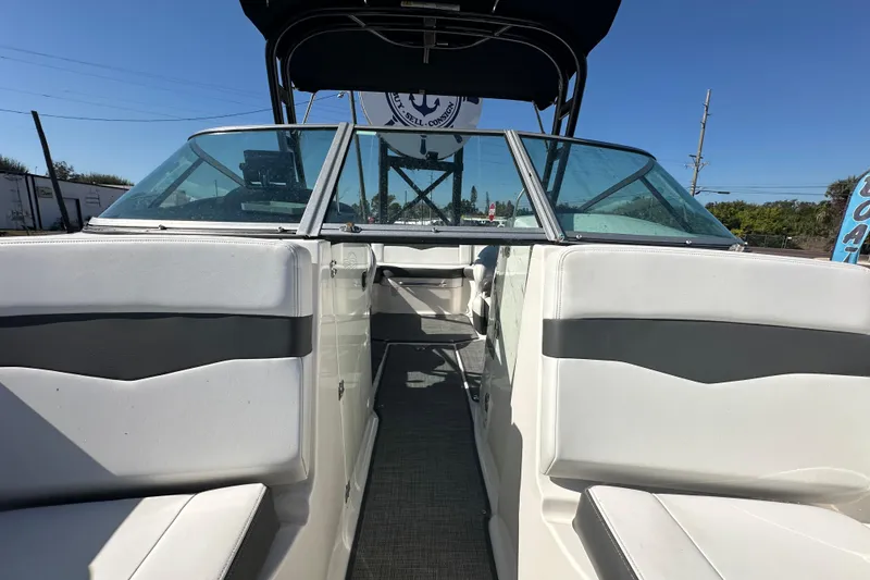 Slide: The Image of 2015 Chaparral 246 boat interior with seating and windshield, under clear blue sky. - 67