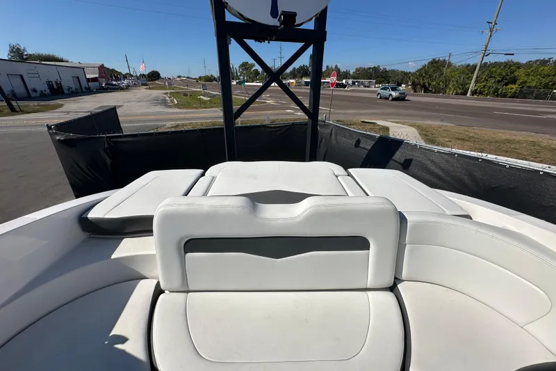 Slide: The Image of 2015 Chaparral 246 boat interior with white seating, parked near a road. - 73