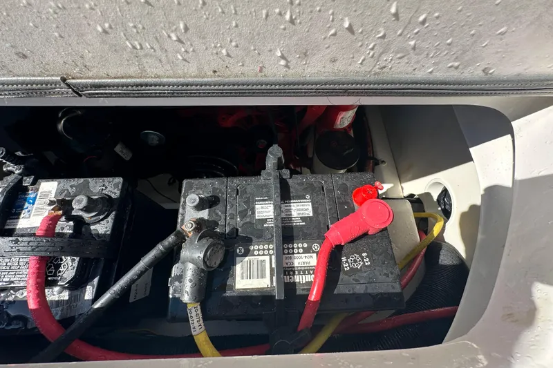 Slide: The Image of Battery compartment of a 2015 Chaparral 246 boat, showing dual batteries with cables. - 77