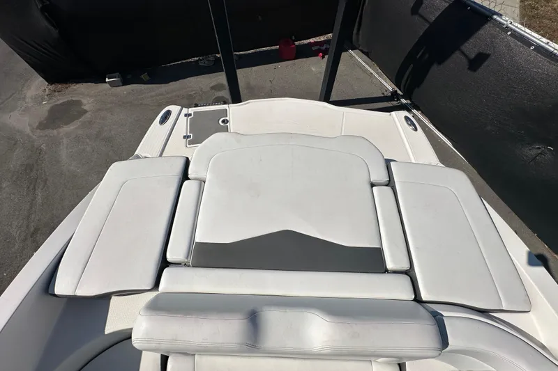 Slide: The Image of 2015 Chaparral 246 boat interior with white cushioned seating and storage area. - 78