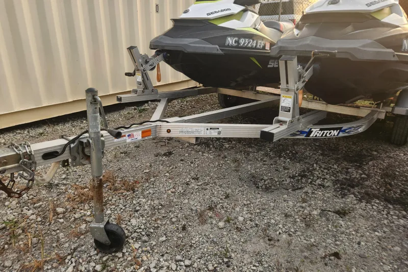Slide: The Image of 2017 Sea-Doo GTI SE 130 jet skis on a Triton trailer, parked on gravel. - 16