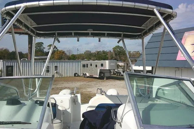 Slide: The Image of 2003 Glacier Bay 2240 Dual Console boat with canopy, parked near trailers and buildings. - 22
