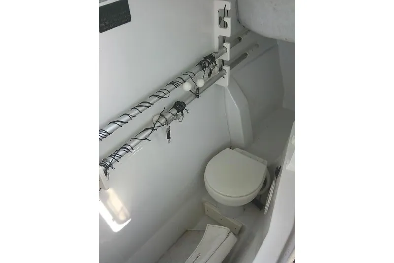 Slide: The Image of 2003 Glacier Bay 2240 Dual Console boat interior with toilet and fishing rod holders. - 44