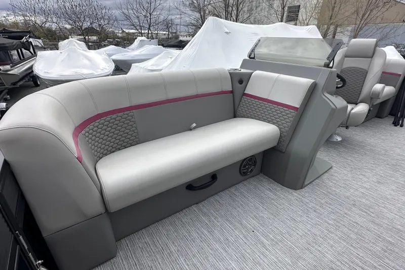 Slide: The Image of 2024 Qwest 8518 RLS boat interior with gray and pink seating, steering console, and covered boats outside. - 7