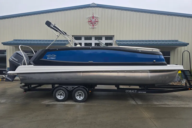 Slide: The Image of 2016 Marker One ML4 pontoon boat on trailer, parked outside a marine building. - 5