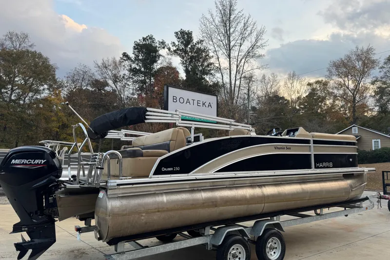 Slide: The Image of 2022 Harris Cruiser 230 pontoon boat on trailer, featuring Mercury engine, outdoors. - 1