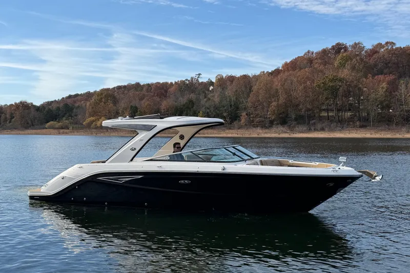 The Image of 2026 Sea Ray SLX 310 boat cruising on a serene lake with autumn foliage. - 0
