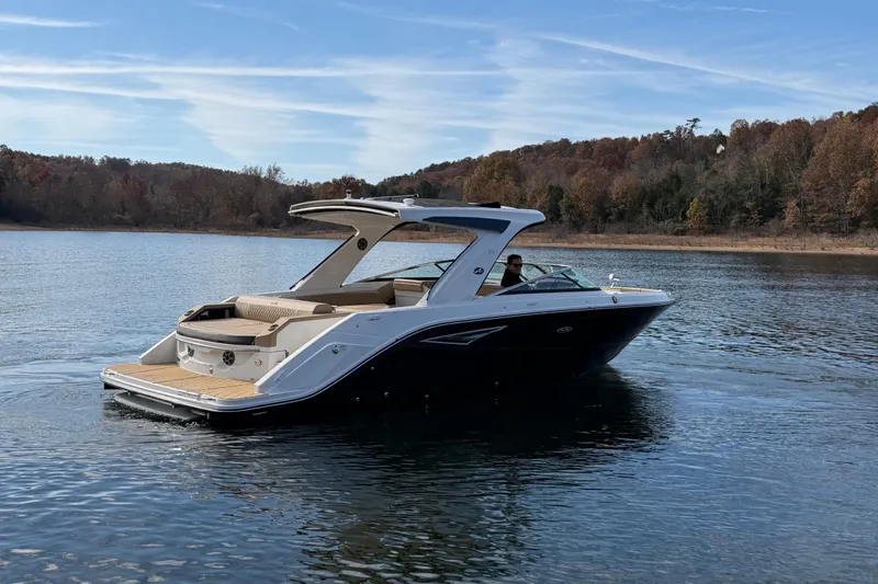 Slide: The Image of 2026 Sea Ray SLX 310 boat cruising on a serene lake with wooded shoreline. - 2
