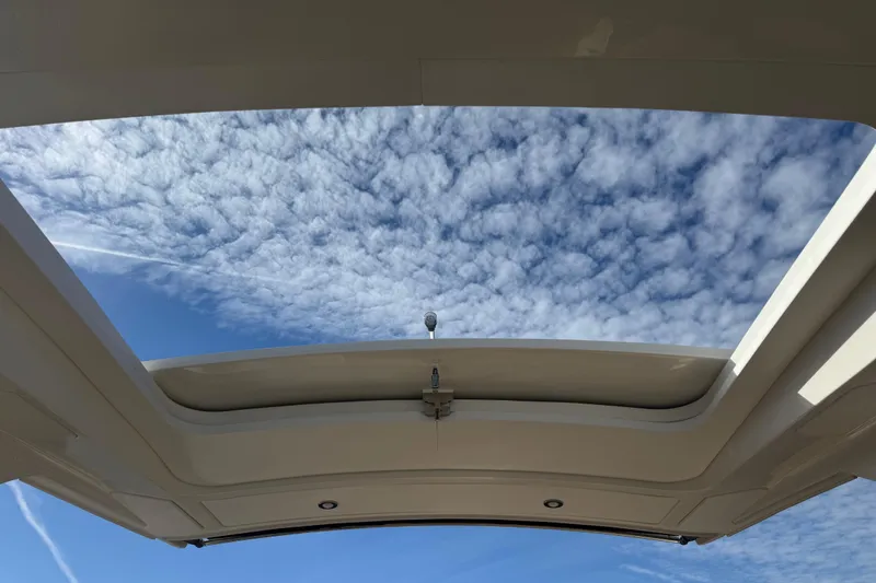 Slide: The Image of 2026 Sea Ray SLX 310 boat with open sunroof under a cloudy sky. - 43