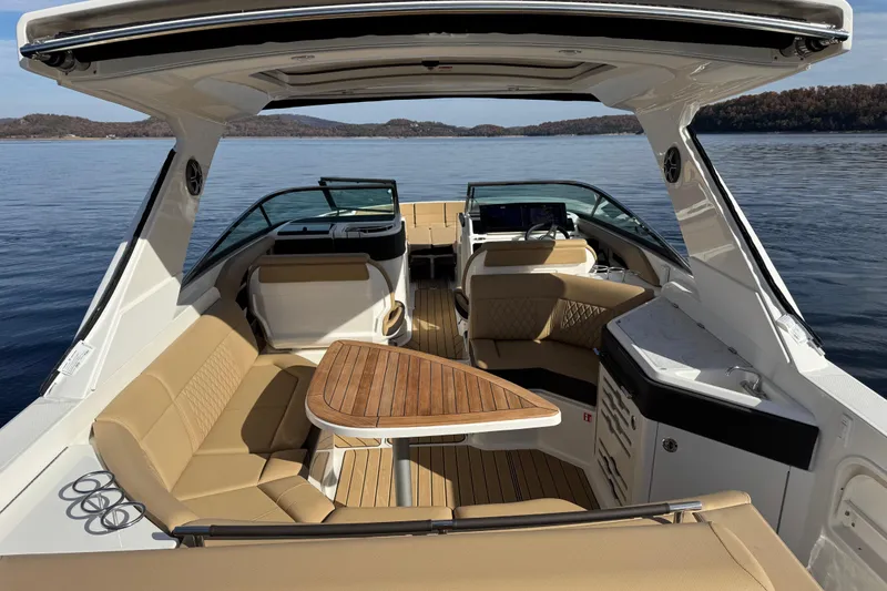 Slide: The Image of 2026 Sea Ray SLX 310 boat interior with luxurious seating and wooden table on calm water. - 8
