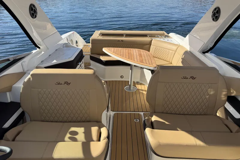 Slide: The Image of 2026 Sea Ray SLX 310 boat interior with tan leather seating and wooden table on water. - 9
