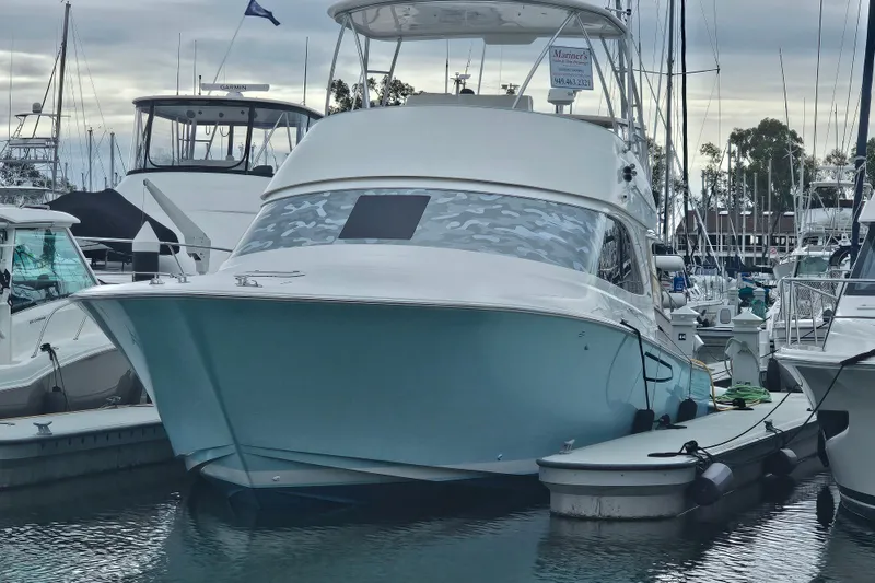 Slide: The Image of 2013 Viking 42 Convertible yacht docked in a marina, surrounded by other boats. - 2