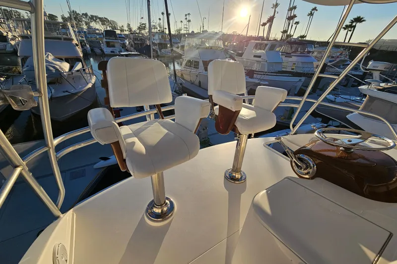 Slide: The Image of 2013 Viking 42 Convertible yacht helm with white captain chairs at sunset in marina. - 23