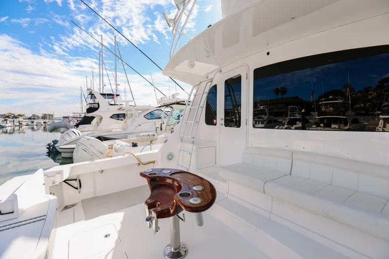 Slide: The Image of 2013 Viking 42 Convertible yacht docked in marina, featuring sleek white design and fishing station. - 47