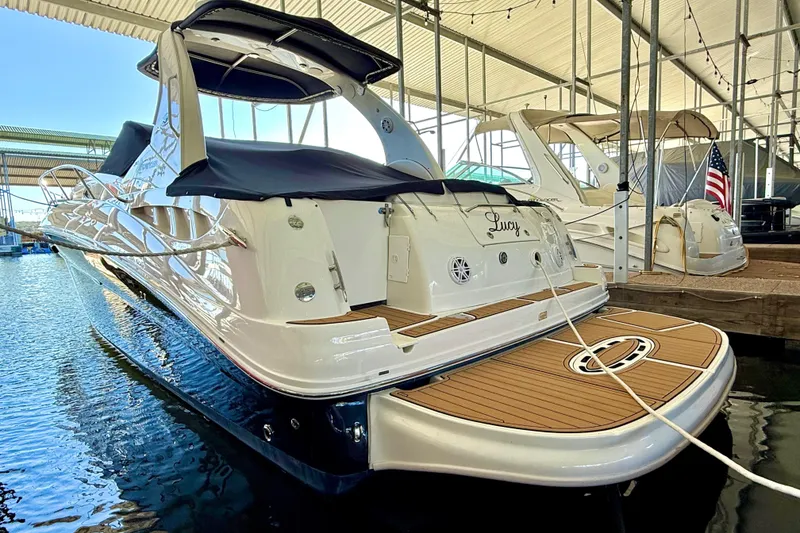 Slide: The Image of 2006 Sea Ray 320 Sundancer docked in a marina, featuring sleek design and spacious deck. - 10