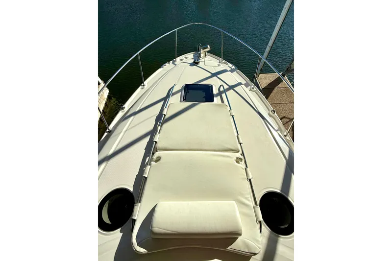 Slide: The Image of 2006 Sea Ray 320 Sundancer boat deck with sun pad, docked by the water. - 17