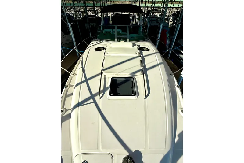 Slide: The Image of 2006 Sea Ray 320 Sundancer boat deck in marina, featuring sleek design and hatch. - 19