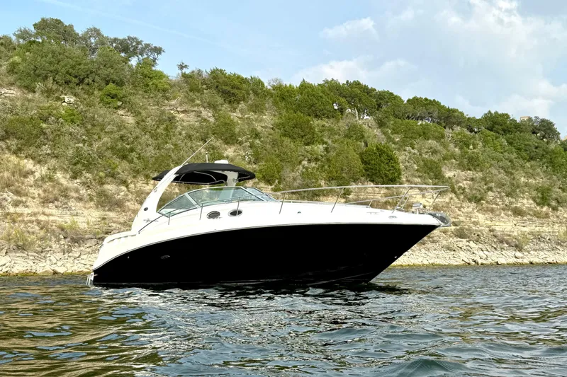 Slide: The Image of 2006 Sea Ray 320 Sundancer yacht on scenic water with rocky shoreline backdrop. - 3
