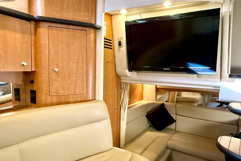 Slide: The Image of Interior of 2006 Sea Ray 320 Sundancer with TV, beige seating, and wooden cabinetry. - 54