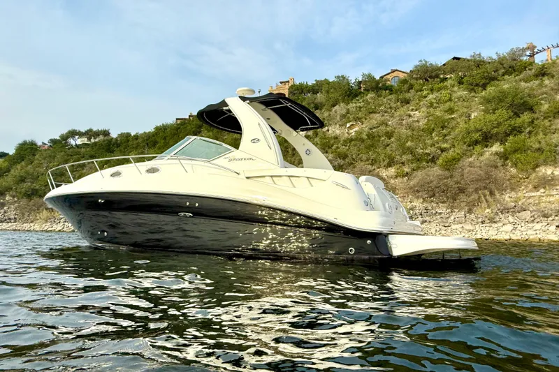 Slide: The Image of 2006 Sea Ray 320 Sundancer yacht on calm water near a rocky shoreline. - 6