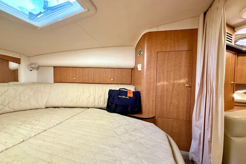 Slide: The Image of 2006 Sea Ray 320 Sundancer cabin interior with bed, wooden cabinets, and natural light. - 62