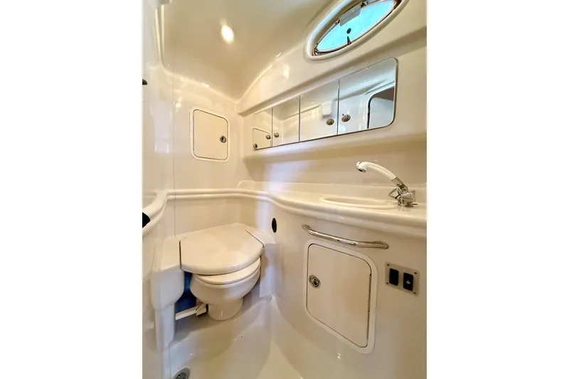 Slide: The Image of 2006 Sea Ray 320 Sundancer bathroom with toilet, sink, and storage cabinets. - 65