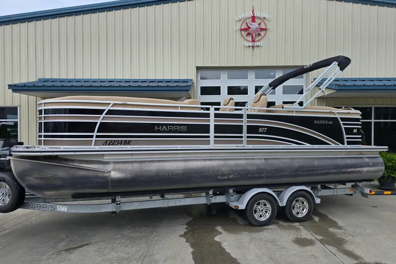 Slide: The Image of 2017 Harris Solstice 240 pontoon boat on trailer outside marine building. - 2