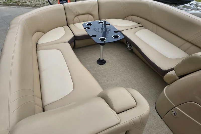 Slide: The Image of 2017 Harris Solstice 240 boat interior with beige seating and a central table. - 7