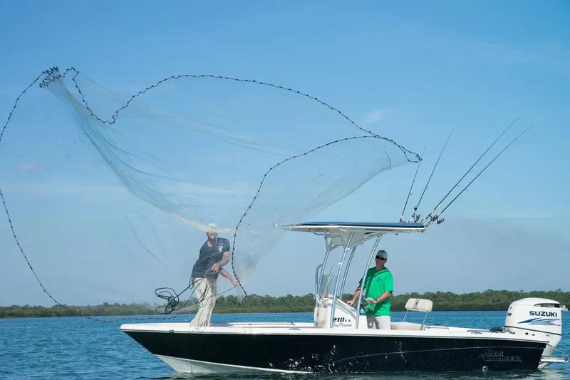 Slide: The Image of 2018 Sea Chaser 21 LX boat with T-top and rod holders, parked near palm trees at sunset. - 6