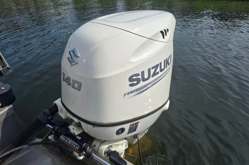 Slide: The Image of Suzuki 140 outboard motor on 2019 Manitou 21 Oasis RF boat in water. - 19