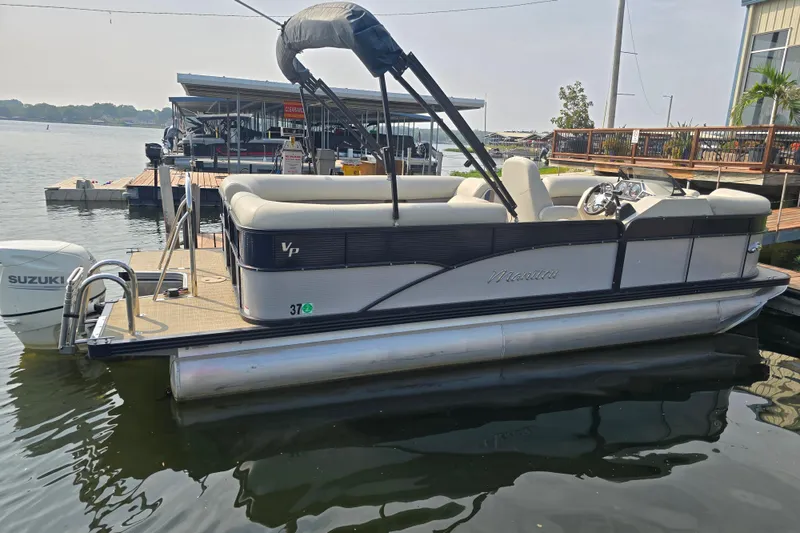 Slide: The Image of 2019 Manitou 21 Oasis RF pontoon boat docked with Suzuki outboard motor. - 4