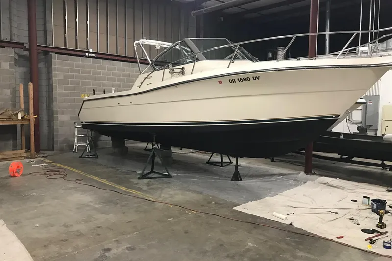Slide: The Image of 1998 Pursuit 2860 Denali boat in a garage, elevated on stands for maintenance. - 10