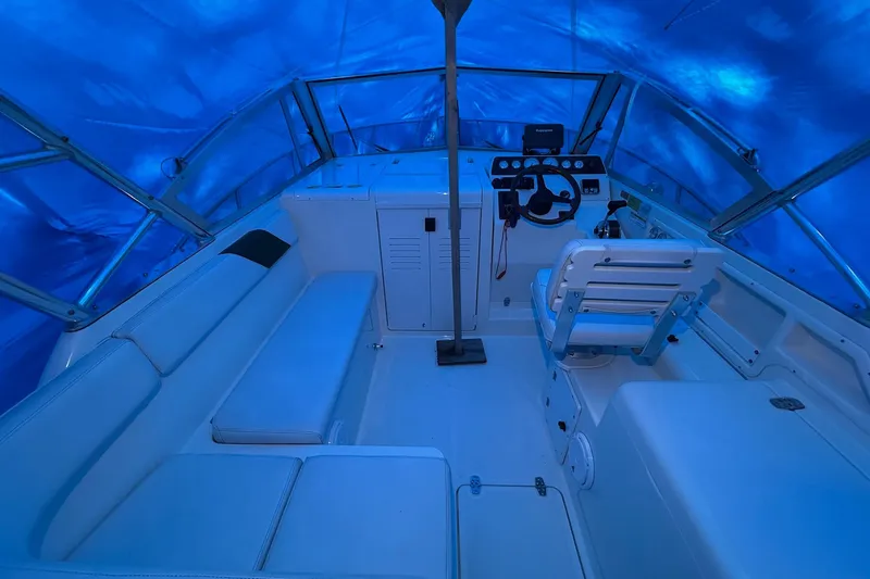 Slide: The Image of 1998 Pursuit 2860 Denali boat interior with blue tarp cover, featuring helm and seating area. - 11