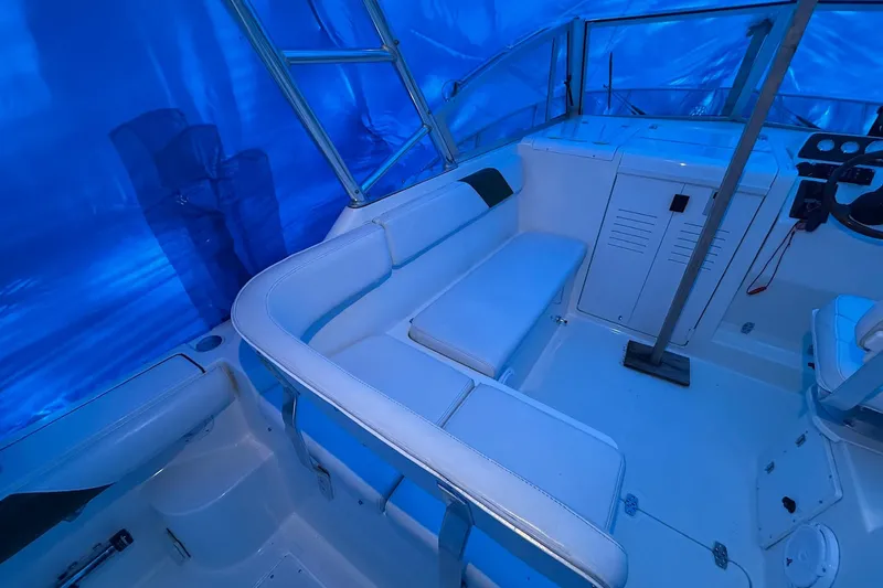 Slide: The Image of 1998 Pursuit 2860 Denali boat interior with white seating under blue cover. - 12