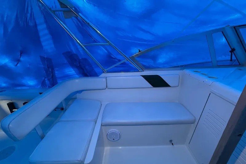 Slide: The Image of 1998 Pursuit 2860 Denali boat interior with white seating under blue tarp. - 13